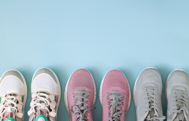 Three pair of sport shoes top view on light blue background with copy space