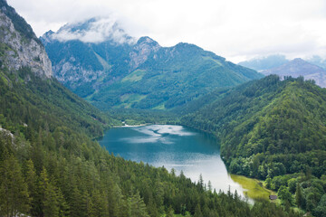View to Leopoldsteinersee mountain lake with turquoise crystal clear water surrounded by forest in beautiful alpine landscape.