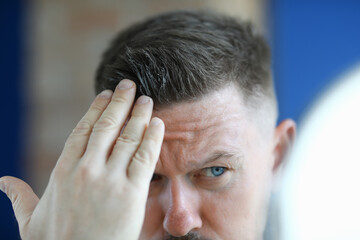 Man applying hair gel to his hair Cosmetics for men concept