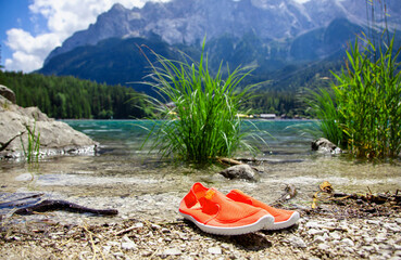 bathing shoes on the shore. in front of lake Eibsee in the bavarian alps near Garmisch Partenkirchen, Bavaria Germany. view on mountain range wetterstein mountains. Wettersteingebirge Zugspitze