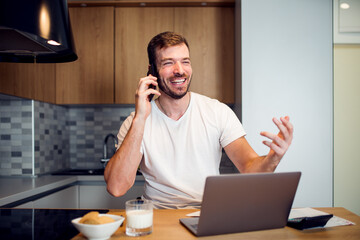 Smiling man working from home with laptop