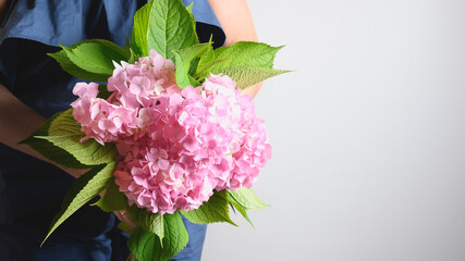 Woman in blue dress with bouquet of pink hydrangea flower. Flowers delivery. Handsome freshly plucked bouquet. Banner with copy space.