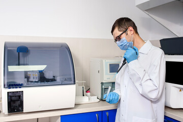 In the hospital laboratories working process, a young man doctor scientists is using micropipette...