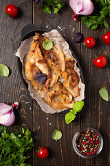 Fried pork bacon in a cast iron pan with tomatoes and spices and onions