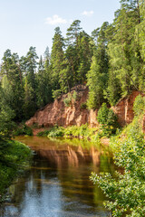 View to the Neļķu (Nelku)  red sanstone cliffs at the river Salaca in Skaņaiskalns (Skanaiskalns) Nature Park in Mazsalaca in July in Latvia