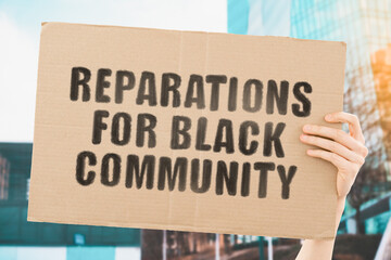 The phrase " Reparations for black community " on a banner in men's hand with blurred background. Demand. Dishonest. Payment. Money. Slaves. Black people. Social inequality. Protest. Tough life
