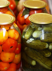 Glass containers with tomatoes and green cucumbers.
