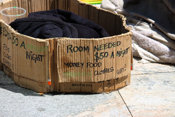 Collection cup and cardboard signage of a homeless man. North Sydney Australia