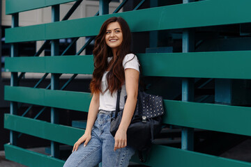 Portrait of smiling pretty girl. Beautiful young woman with backpack posing outdoor