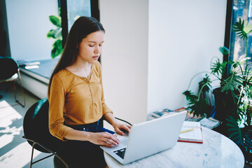 Pensive female student searching information for report browsing  web site on laptop...