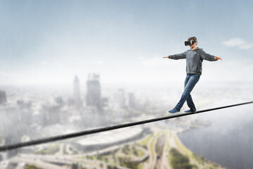 Man wearing virtual reality goggles and balancing on rope