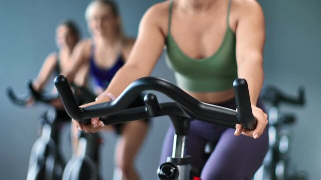 Closeup athletic female body spinning pedals of stationary bike. Shot on RED Raven 4k Cinema Camera