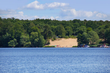 Boating on Peetz lake (Peetzsee) in Gruenheide in federal state Brandenburg, view to the sand beach, Germany

