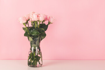 The vase with beautiful roses on pink background.