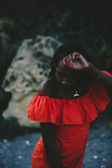 An elegant and beautiful young black woman in a red dress in a shore background in summer. 