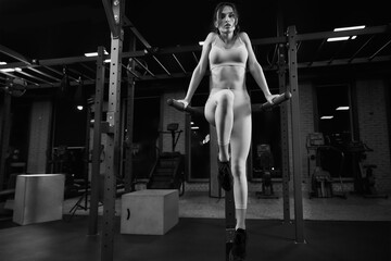 Woman posing on parallel bars in gym.