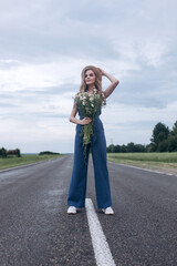 Fototapeta premium Beautiful blondie woman natural face in hat on the road with flowers