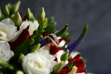 Two wedding rings on a wedding bouquet of white roses, close-up.