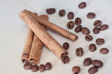 Cinnamon sticks and coffee beans. Roasted coffee beans on a wooden background. Light tree background.