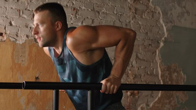 fitness, sport, bodybuilding and people concept - young man doing triceps dip exercise on parallel bars in gym