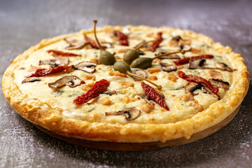 Close-up of tasty pizza with Mozzarella cheese, sun-dried tomatoes, mushrooms, cappers and grilled chicken