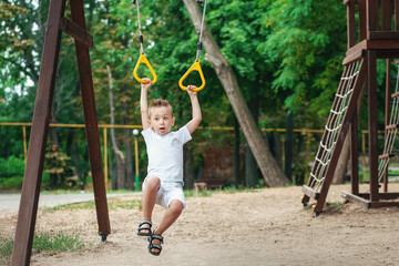 Portrait of cute caucasian boy. The child is training with gymnastics rings