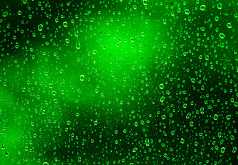 Natural green background with rain drops on the glass