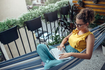 Young woman working on balcony. Young business woman using laptop computer to take video conference.