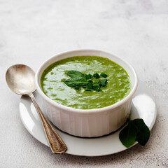 Creamy green spinach soup in a white bowl, spring healthy green creamy soup. Detox, dieting or clean eating food.