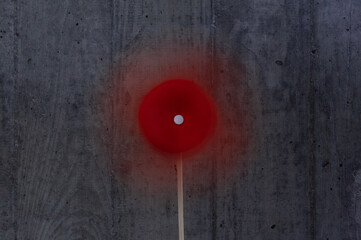 red paper windmill in front of concrete wall blurred motion effect