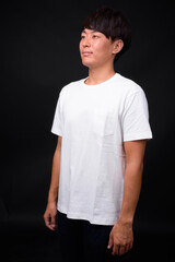 Young handsome Asian man against black background