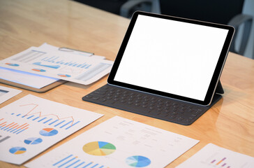 Close - up shot of Mockup modern tablet blank screen with data chart on the desk.
