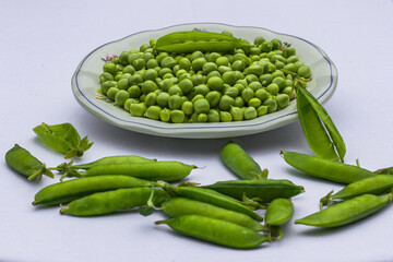 Green Peas. Green background. Peas background. Top view.Green pea in bowl on white background copy space. Fresh organic green peas on a round white plate. Vegetable harvesting