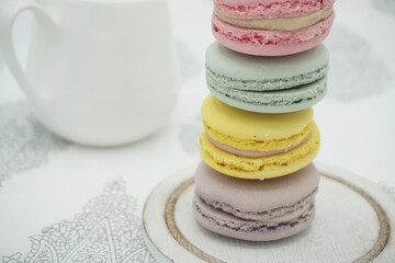 Handmade flavored French macarons on the plate, pastel colors, white milk pottery in the background, landscape frame 