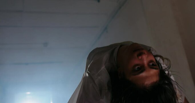 Scary female psychopath crawling in corridor of cursed house with unnatural moves. Exorcist girl awaken by demon - halloween concept 4k footage