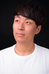 Fototapeta premium Young handsome Asian man against black background