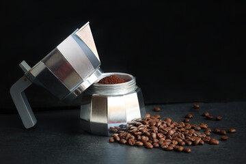 Coffee in a moka pot with coffee beans and ground coffee on blur dark background.