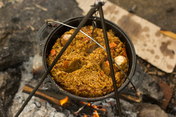 Fototapeta na wymiar Cooking camping outdoor meal in an open fire in a travel pot with blaze. Dinner during travel.