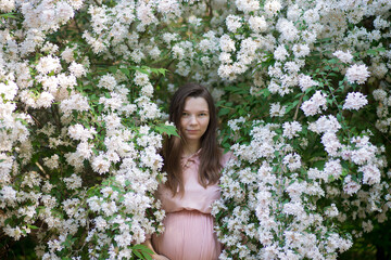 Pregnant woman in the apple orchard is holding tummy and apple blossoming branch