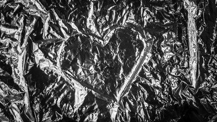 Abstract background. Heart shape in the middle of a crumpled aluminum foil.