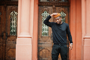 African red haired man wear black outfit posing outdoor.