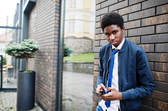 African man wear in tie and casual outfit posing outdoor with mobile phone.