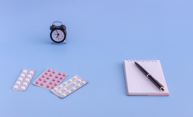 pills, watch, pen, writing sheets on a blue background. the concept of medicine, fulfillment of doctor's instructions