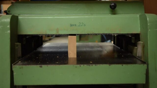 Carpenter using machine for planing a piece of wood