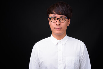 Young handsome Asian businessman against black background