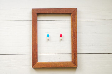 Close up Red and Blue pill on a wooden frame. Choose your Mood today Concept