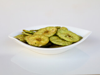 Green color banana chips with hot green chili flavor in a white bowl against white background