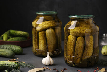 Marinated cucumbers in glass jars on a dark background, harvest for the winter, horizontal orientation