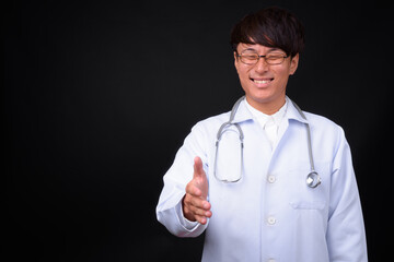 Young handsome Asian man doctor against black background