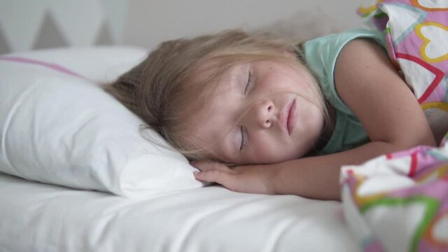 The little girl sleeps sweetly in her bed at home. Close-up of a sleeping child